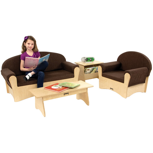 A girl sitting on a brown wood couch reading a book.