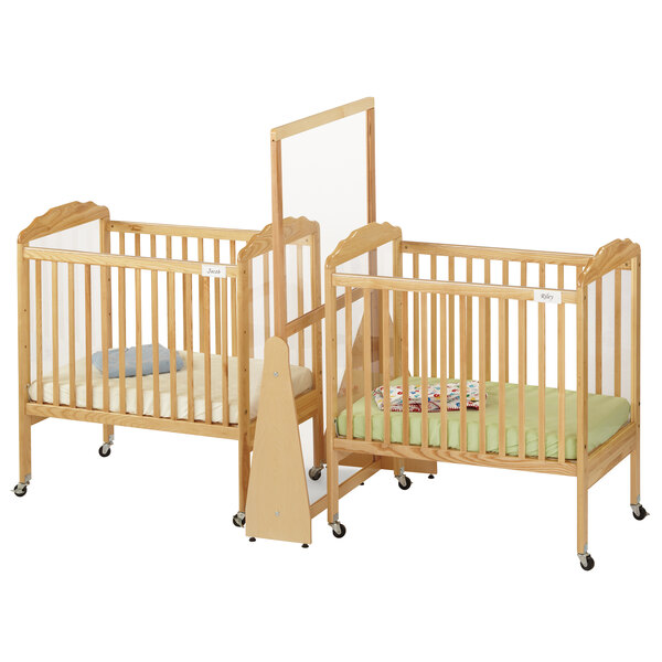 A Jonti-Craft wooden crib divider on wheels separating two cribs.