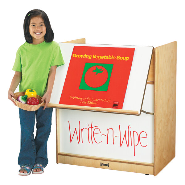 A young girl uses a Jonti-Craft wood book display with a write-n-wipe board.
