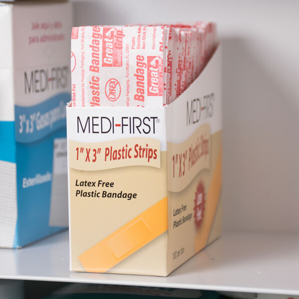 A box of Medique plastic bandage strips on a shelf.