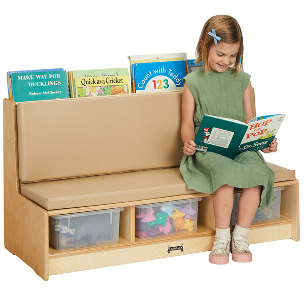 A girl sitting on a Jonti-Craft wood literacy couch with books in clear tubs.