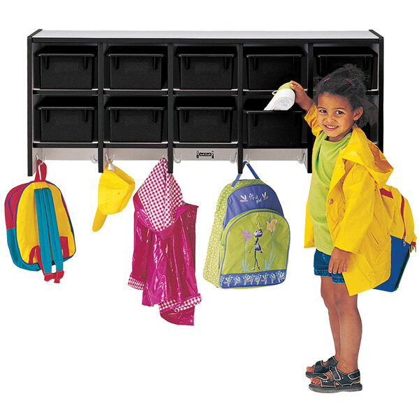 A little girl standing next to a Rainbow Accents black laminate coat rack with double hooks.