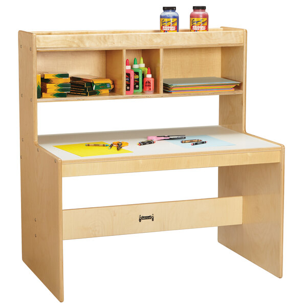A Jonti-Craft children's wood dual writing desk with a shelf and stationery.