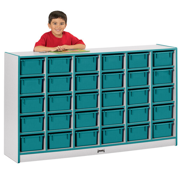 A young boy in a red shirt standing next to a teal and gray Rainbow Accents mobile storage cabinet.