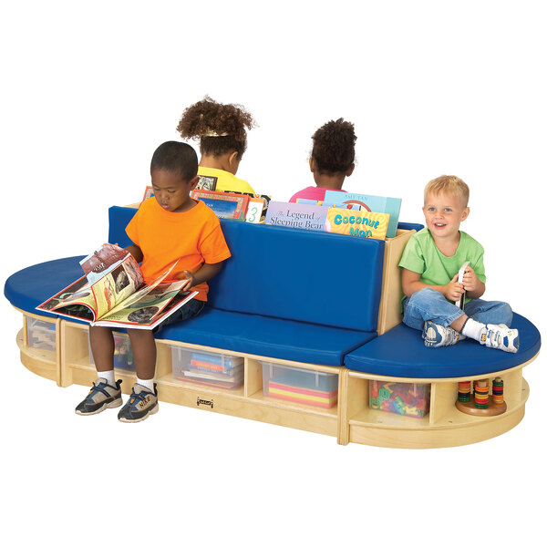 Children sitting on a Jonti-Craft wood bench with blue padded seating reading books.