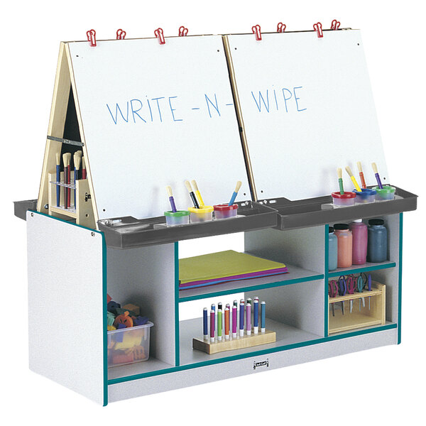 A teal 4-station art center with colorful papers and a white board with writing on it.