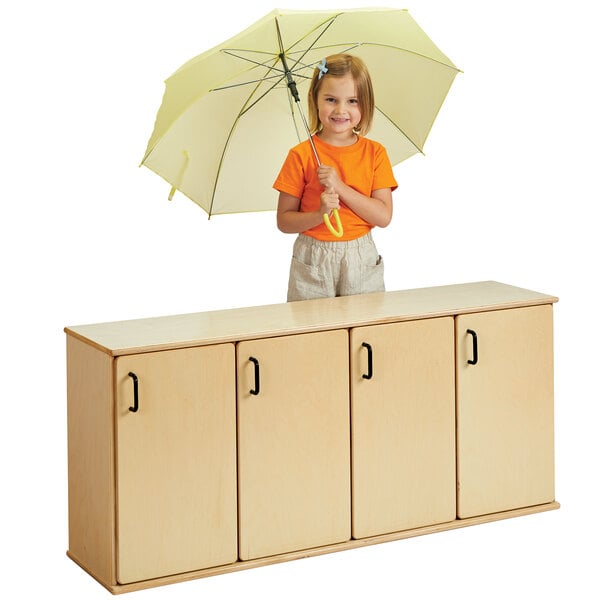 A young girl holding an umbrella in front of a natural wood Young Time Stacking Locker.