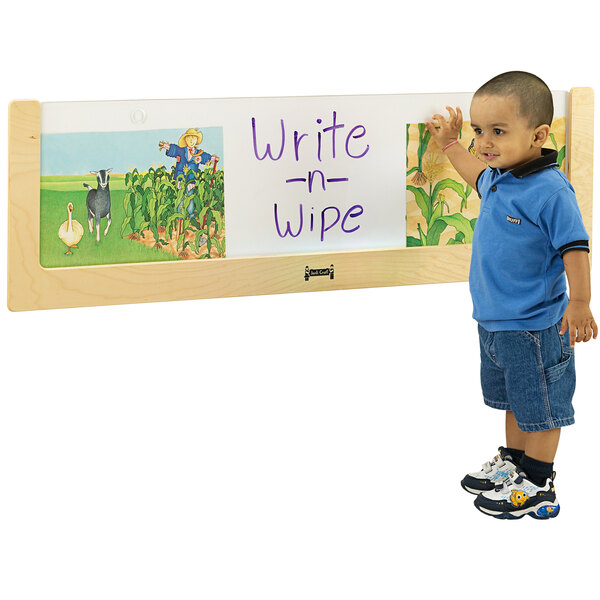 A young boy wearing a blue shirt writing on a Jonti-Craft Write-n-Wipe board.