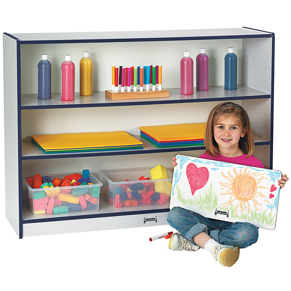 A young girl holding a Rainbow Accents navy bookcase with colorful accents.
