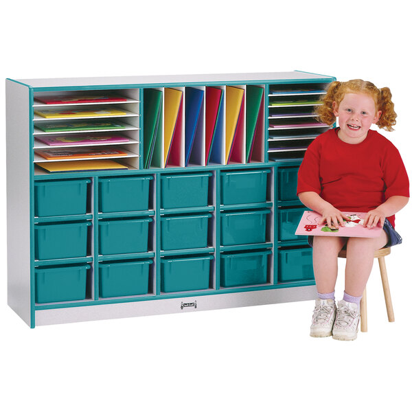 A girl sitting on a stool in front of a Rainbow Accents teal storage cabinet with trays.