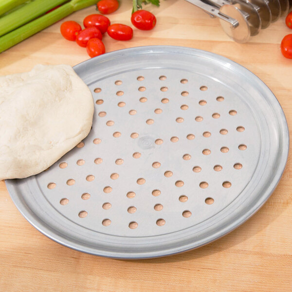 An American Metalcraft wide rim pizza pan with dough on it.