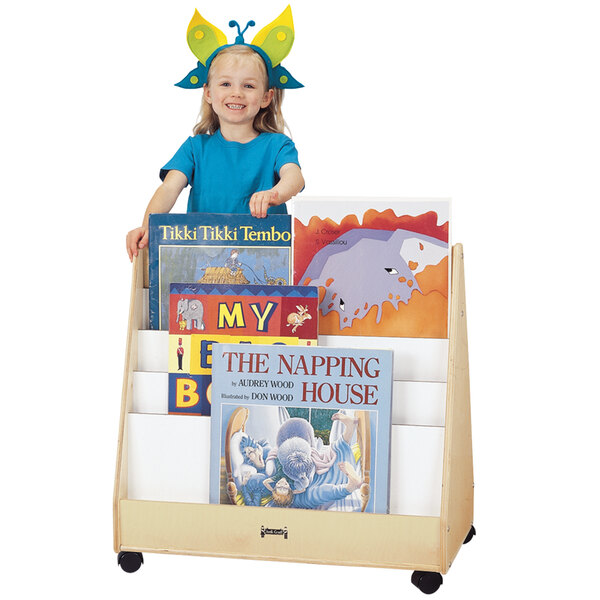 A girl standing next to a Jonti-Craft mobile wood book rack.