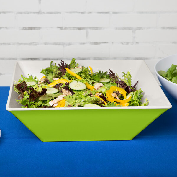 A green Keywest melamine bowl filled with salad on a white table.
