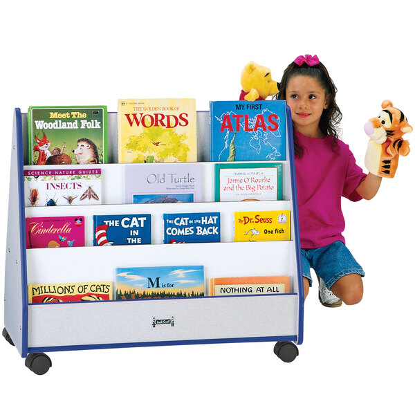 A girl sitting in a book stand with a stuffed tiger reading a book.