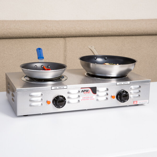 An APW Wyott double electric hot plate with two pans on it.