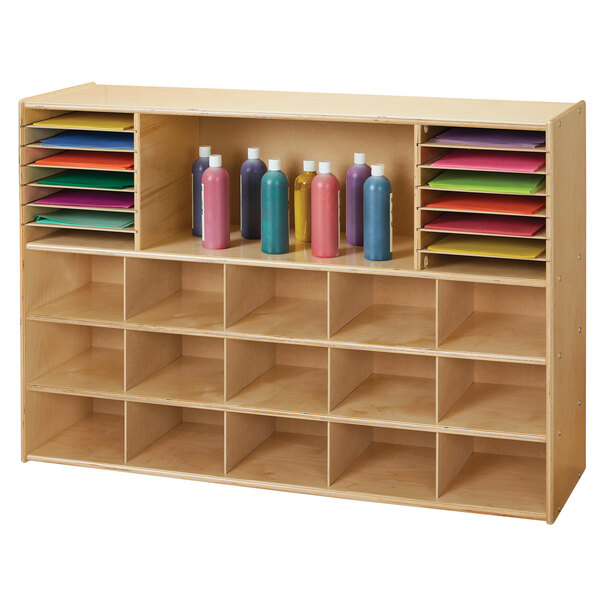A Young Time natural wooden sectional cubbie storage unit with colorful bottles and paper.