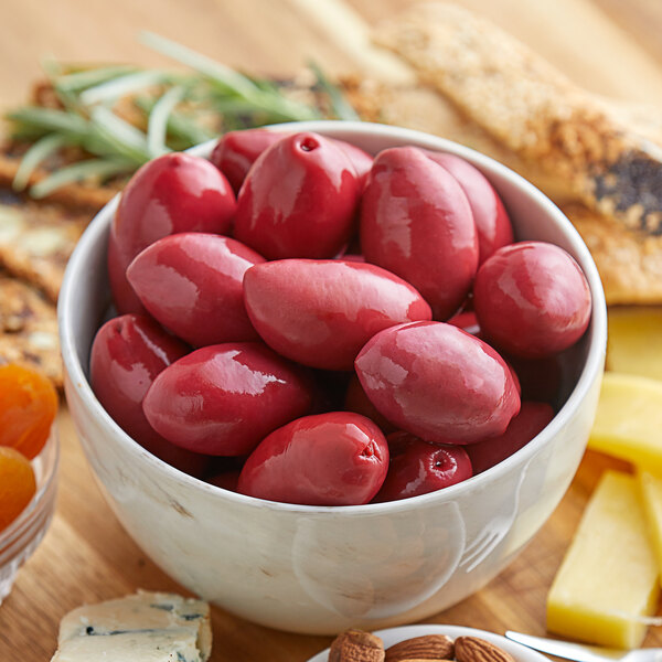 A bowl of red Frutto d'Italia Cerignola olives on a table.