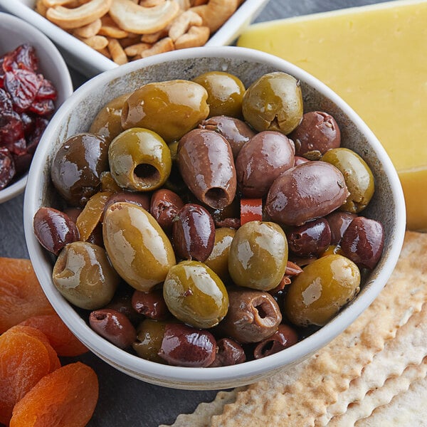 A bowl of Frutto d'Italia green olives on a table with cheese and crackers.