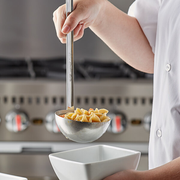 A person using a Vollrath stainless steel ladle to serve pasta from a bowl.