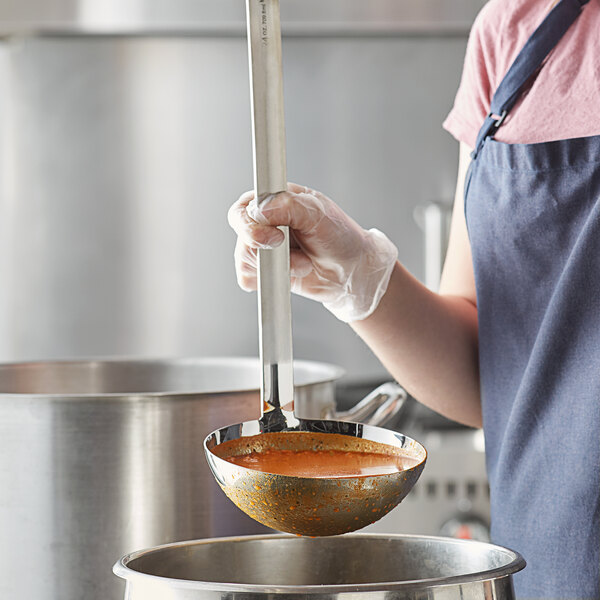 A person using a Vollrath stainless steel ladle to serve soup in a pot.