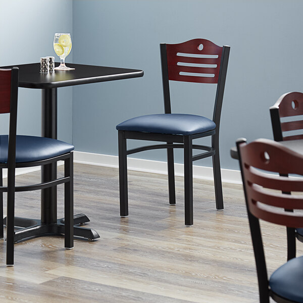 A Lancaster Table & Seating Bistro chair with blue vinyl seat and mahogany wood back on a brown surface.