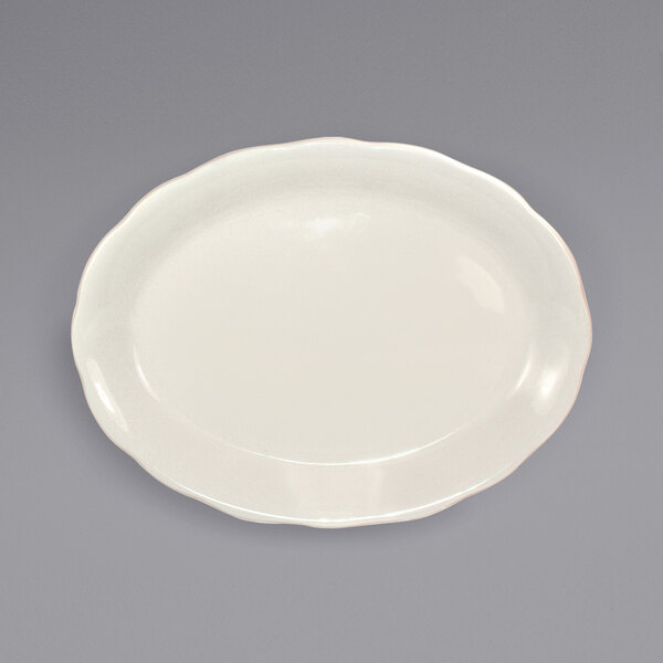 An International Tableware ivory stoneware platter with scalloped edges on a gray surface.