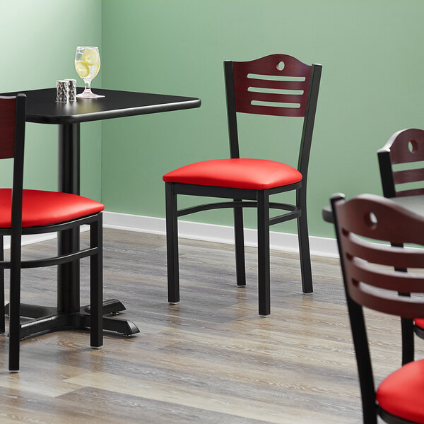 A Lancaster Table & Seating black bistro chair with red vinyl seat and mahogany wood back.