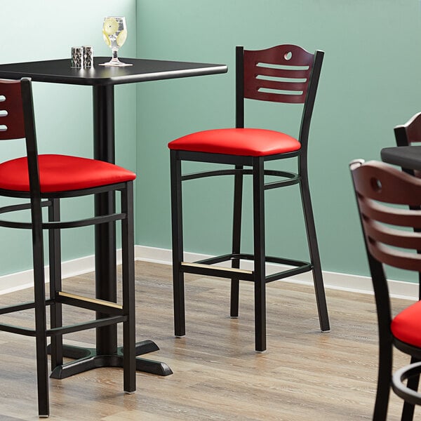 The detached red vinyl seat of a Lancaster Table & Seating Bistro Bar Stool.