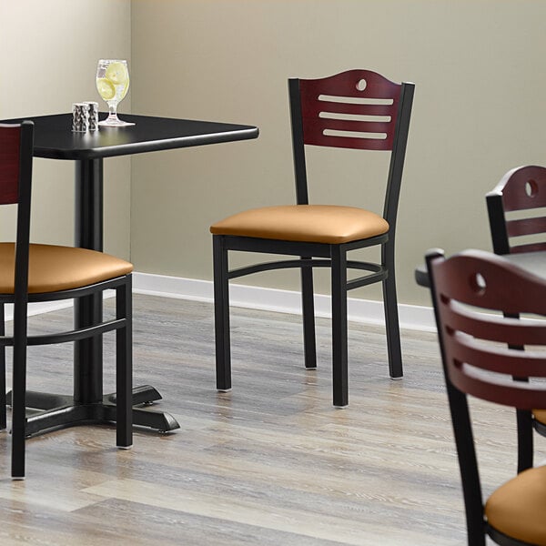 A Lancaster Table & Seating black bistro chair with light brown vinyl seat and mahogany wood back.
