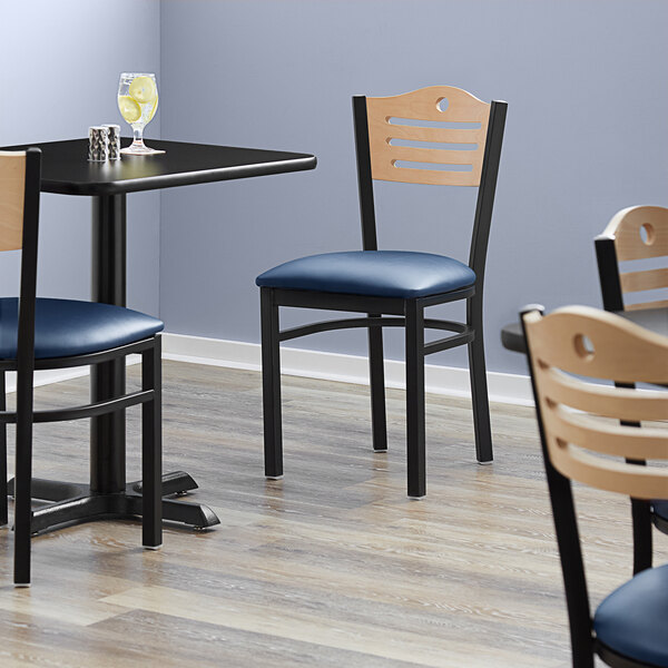 A Lancaster Table & Seating black bistro chair with a navy vinyl seat and natural wood back.