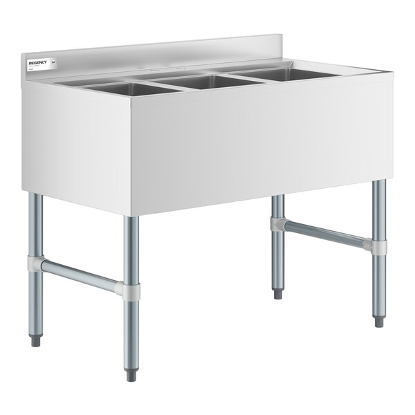 A stainless steel three-compartment sink with a backsplash and four metal legs.