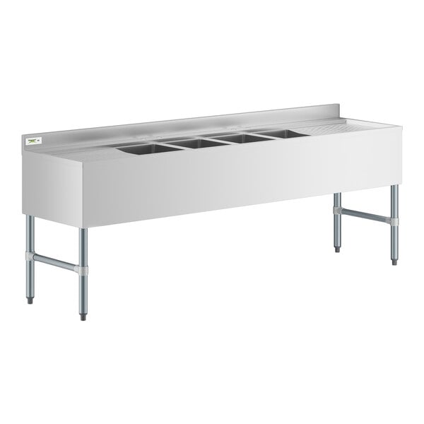 A white rectangular stainless steel Regency underbar sink with two drainboards and four bowls.