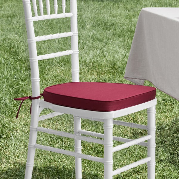 A white chair with a Lancaster Table & Seating red cushion.