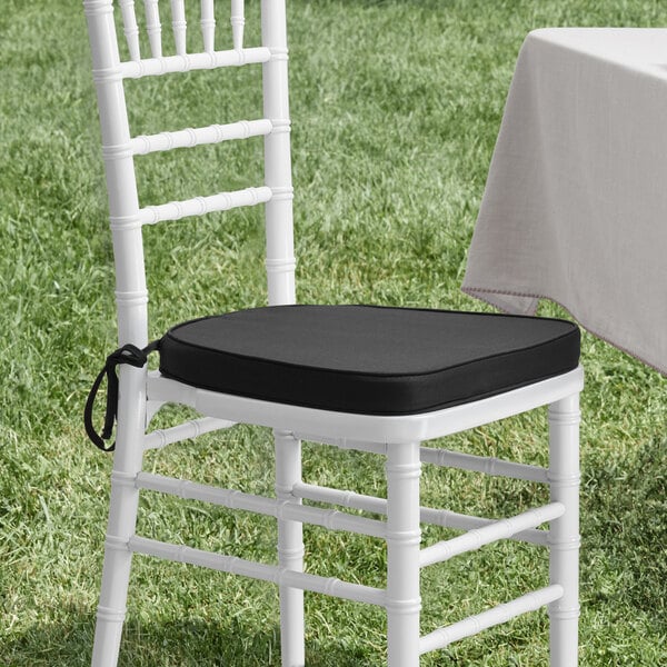 A white chair with a Lancaster Table & Seating black cushion on the seat.