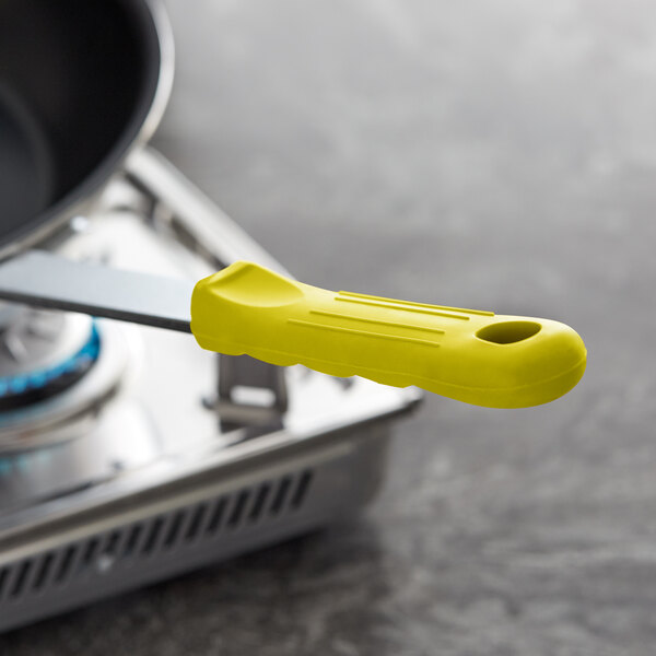 A yellow removable silicone sleeve with lines on a pan handle.