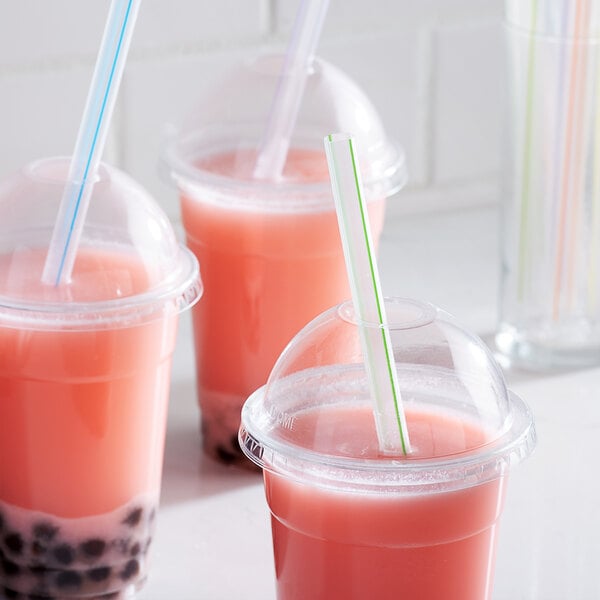 A group of plastic cups with pink bubble tea, each with a Choice multicolor striped straw.