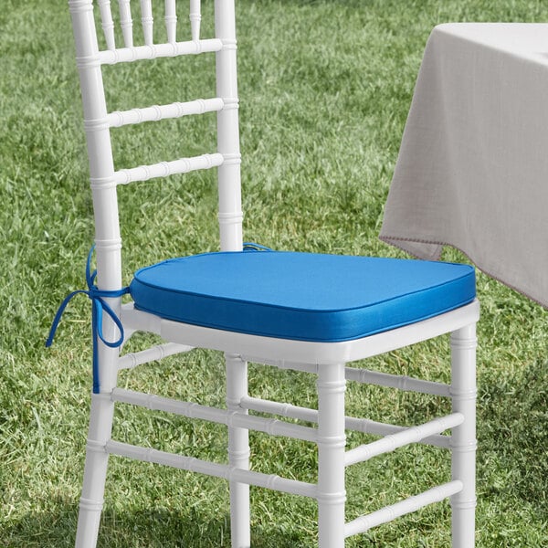 A Lancaster Table & Seating Blue Chiavari Chair Cushion on a white chair.