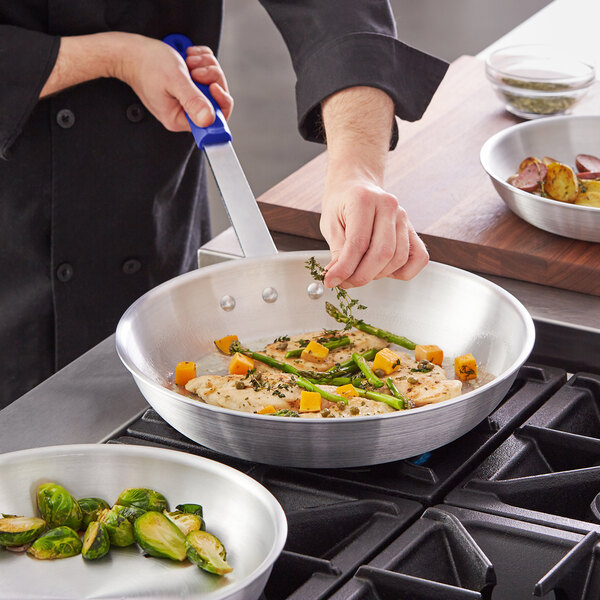 A person cooking brussels sprouts in a Choice aluminum fry pan.