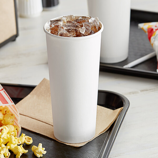 A white Choice paper cold cup with soda and ice on a tray with popcorn.
