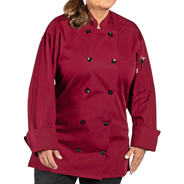 A woman wearing a burgundy Uncommon Chef long sleeve chef coat with 10 buttons.
