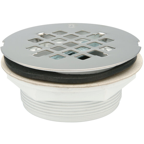 A close-up of a Zurn PVC shower drain with a round metal strainer with a hole in it.