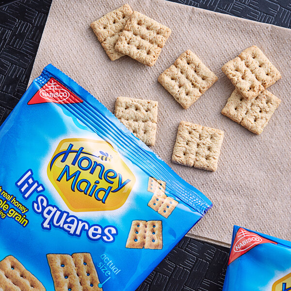 A blue bag of Nabisco Honey Maid Lil Squares crackers on a table with a napkin.