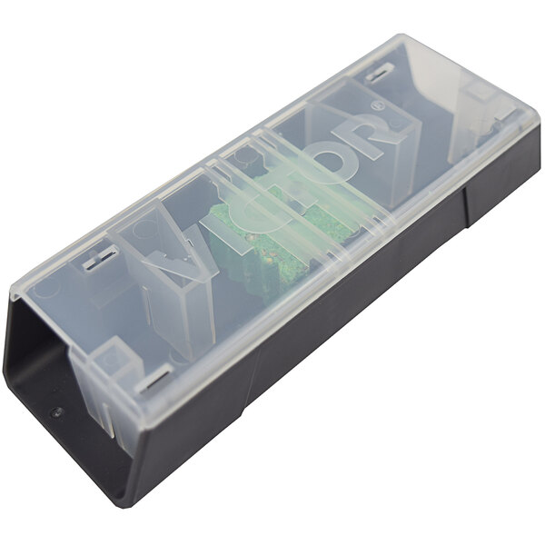 A transparent plastic container with a black and green Victor Pest mouse bait station inside.