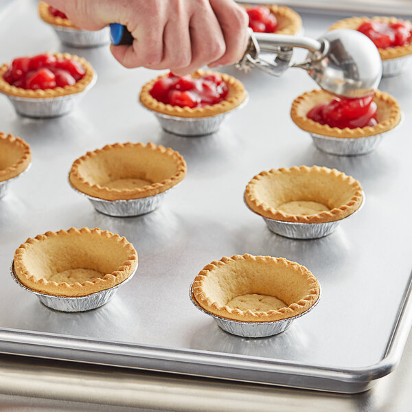 A hand uses a blue pastry cutter to make Keebler Ready Crust tart shells.