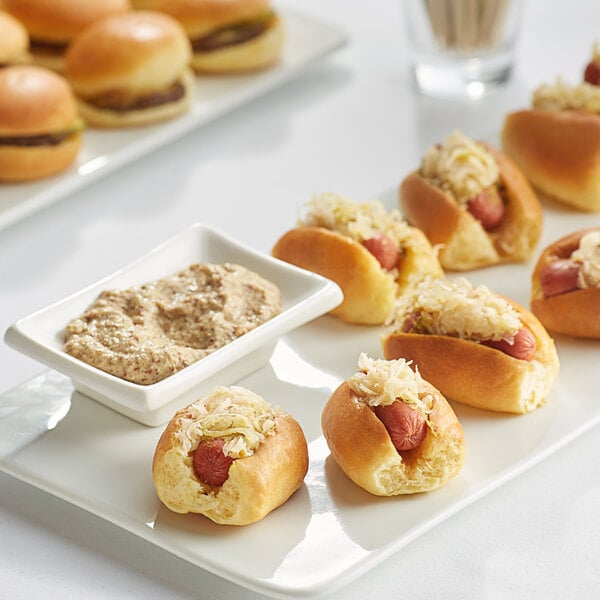 A tray of Les Chateaux de France mini franks topped with sauerkraut and cheese with dipping sauce.