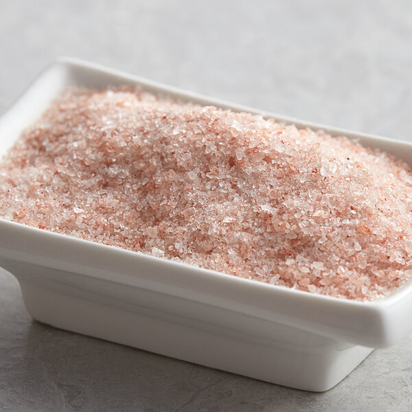 A bowl of Regal Medium Grain Pink Himalayan Salt on a table.