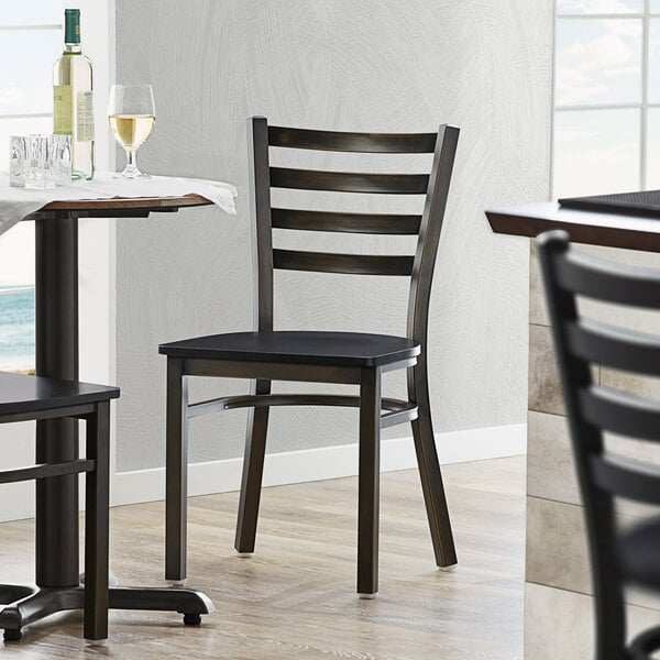 A Lancaster Table & Seating distressed copper ladder back chair with a black wood seat at a table in a restaurant.