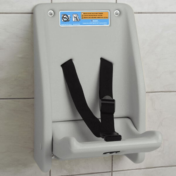 A grey Koala Kare child protection seat with a black strap attached to a white wall.