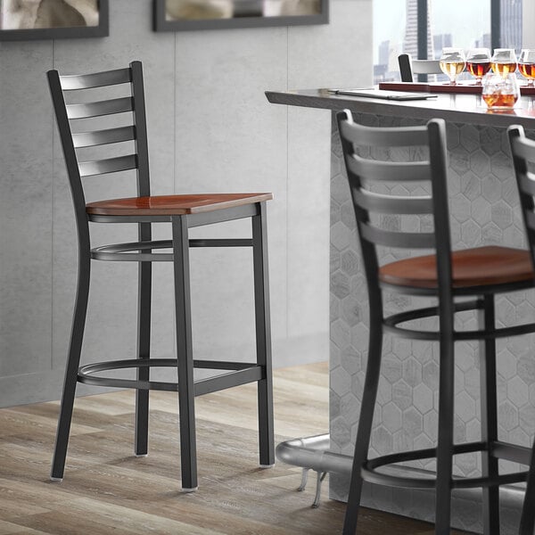 A Lancaster Table & Seating black bar stool with a wooden seat and back.