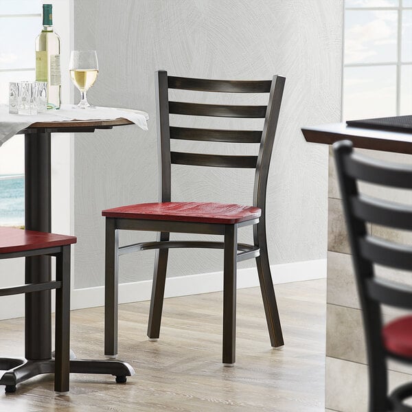 A Lancaster Table & Seating ladder back chair with a mahogany wood seat at a restaurant table with wine bottles.
